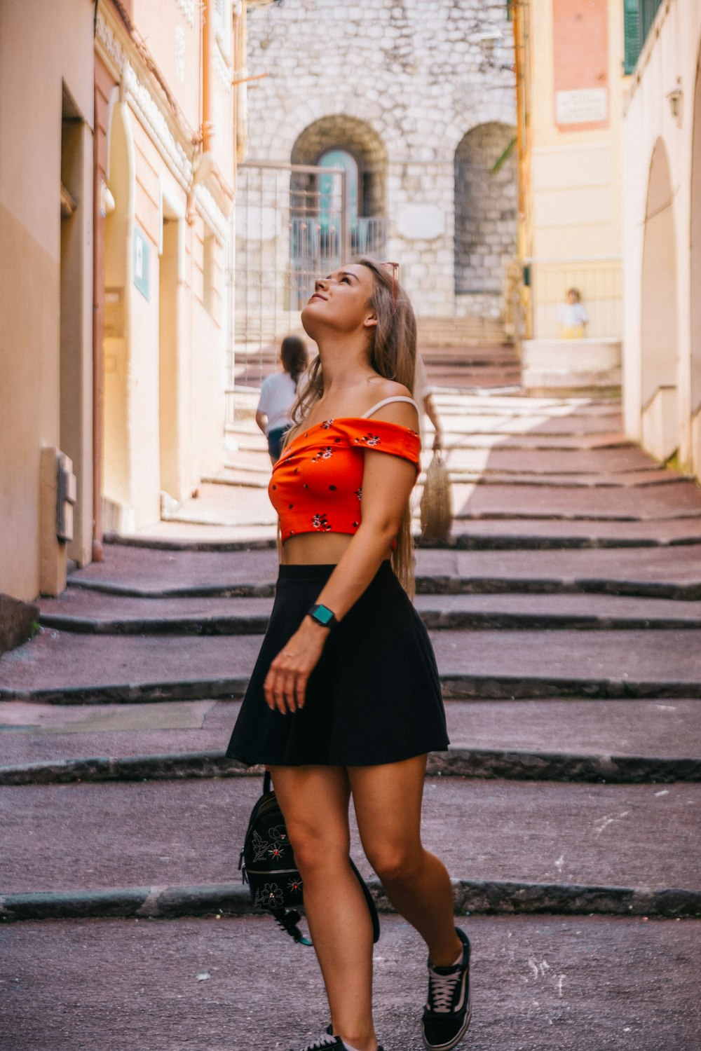 Femme en robe rouge et noire debout sur une voie piétonne pendant la journée