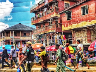 A lively street scene in Sekondi-Takoradi with colorful market stalls and people engaging in daily life under bright Ghanaian flag colors.