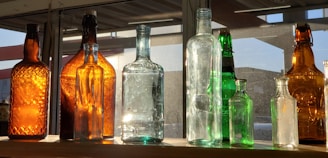 Colorful insulated water bottles lined up on a shelf with sunlight streaming through a nearby window.