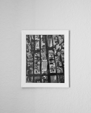 Aerial view photo of an urban cityscape framed in a simple white frame and hung on a textured white wall.
