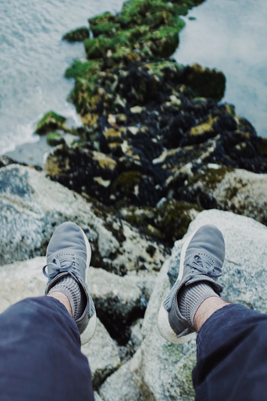person in blue pants and white sneakers sitting on rock in North Vancouver Canada