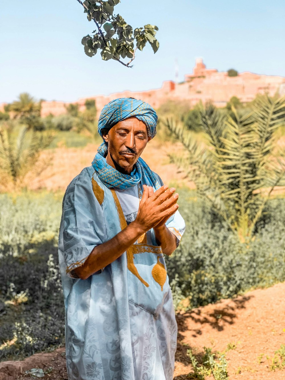 woman in blue and green hijab standing on brown field during daytime