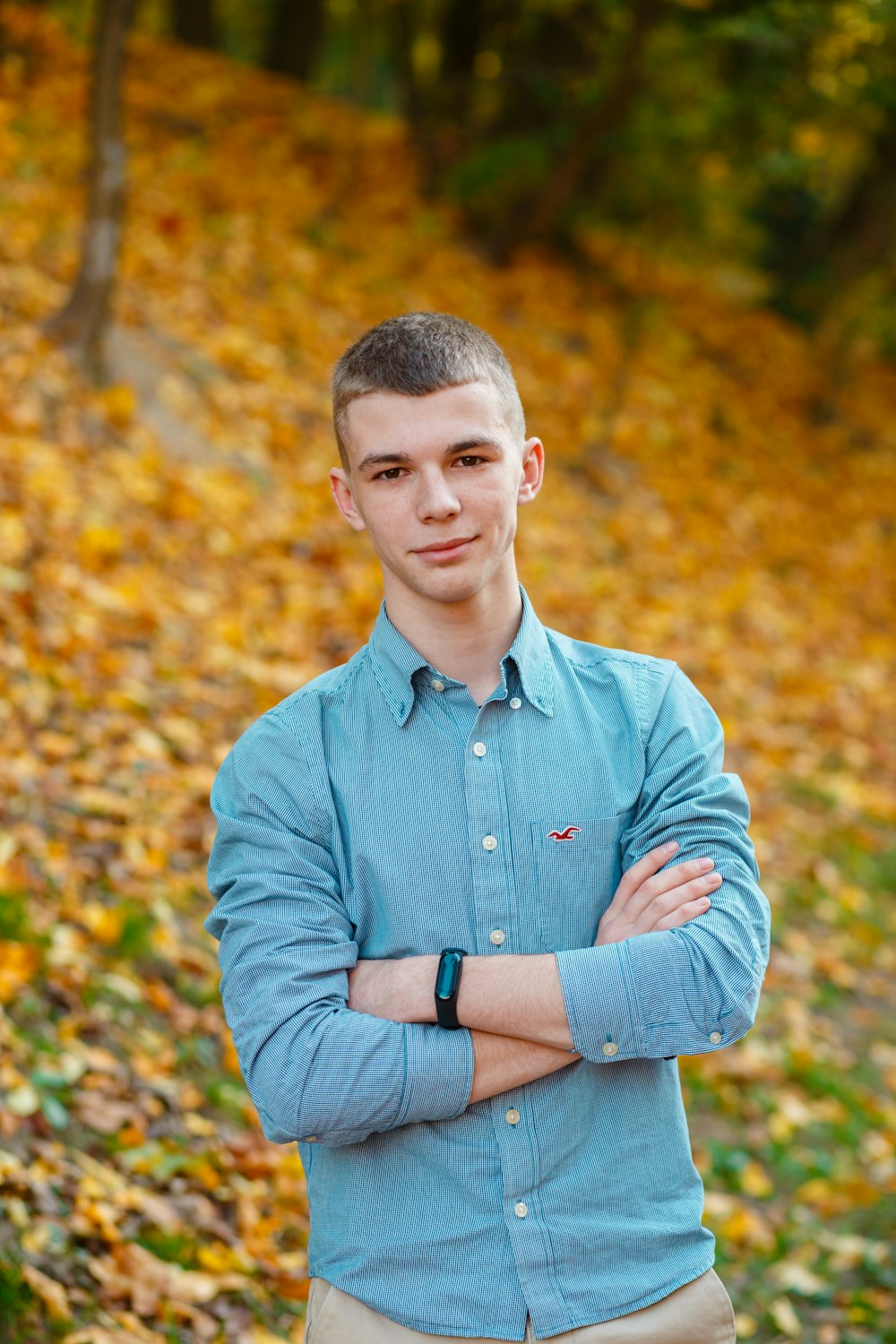 man in blue dress shirt standing near brown leaves during daytime