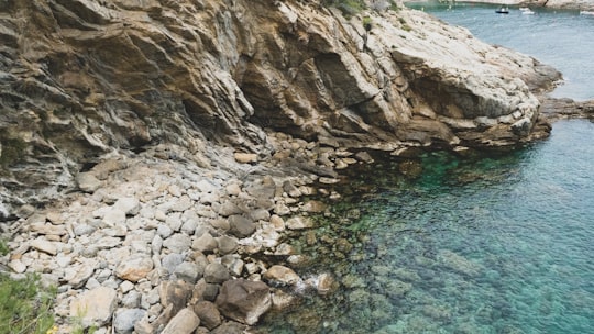 brown rocky mountain beside body of water during daytime in Costa Brava Spain