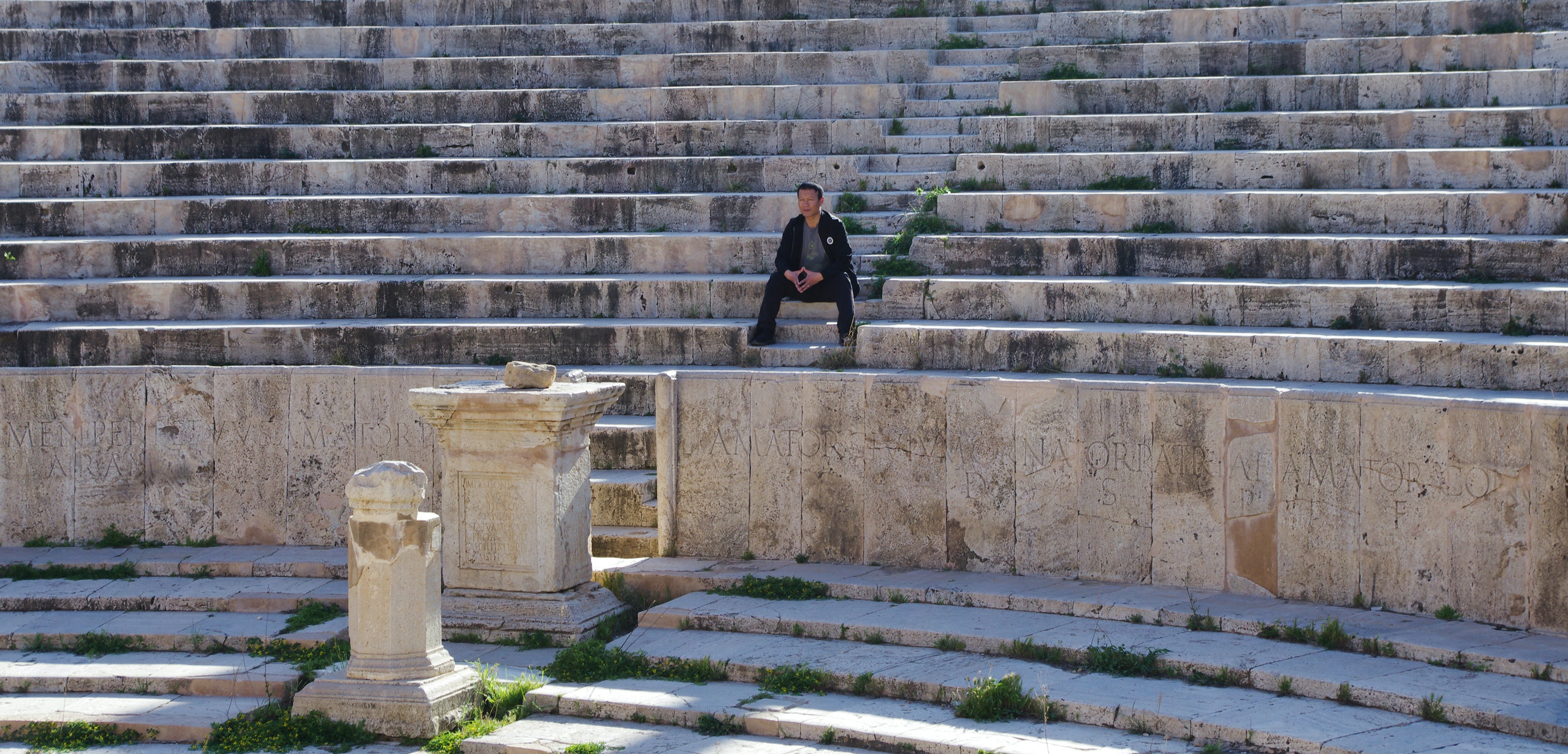 woman in black jacket and black pants sitting on gray concrete stairs, 