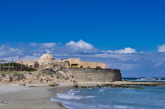 brown concrete building near sea under blue sky during daytime