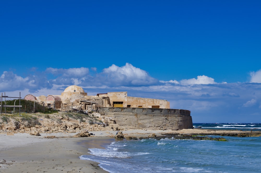 brown concrete building near sea under blue sky during daytime