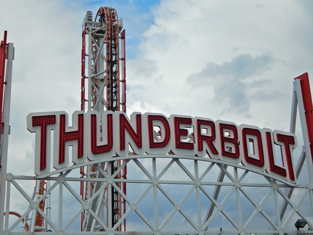 a sign that says thunder bolt on top of a roller coaster