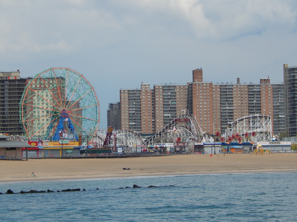 people on beach near ferris wheel during daytime