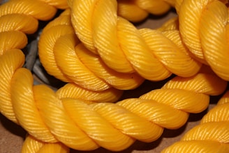 Thick strands of bright yellow rope are tightly coiled and interwoven in a detailed and textured manner, showcasing the rope's twisted pattern.