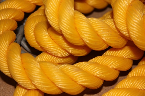 Thick strands of bright yellow rope are tightly coiled and interwoven in a detailed and textured manner, showcasing the rope's twisted pattern.