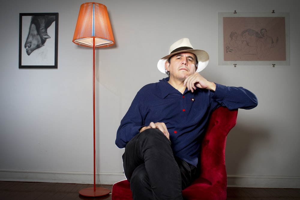 a man sitting in a chair with a hat on