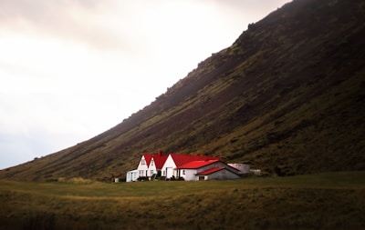 white and red house near green mountain under white sky during daytime