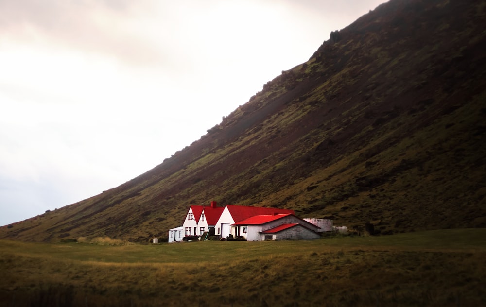 white and red house near green mountain under white sky during daytime