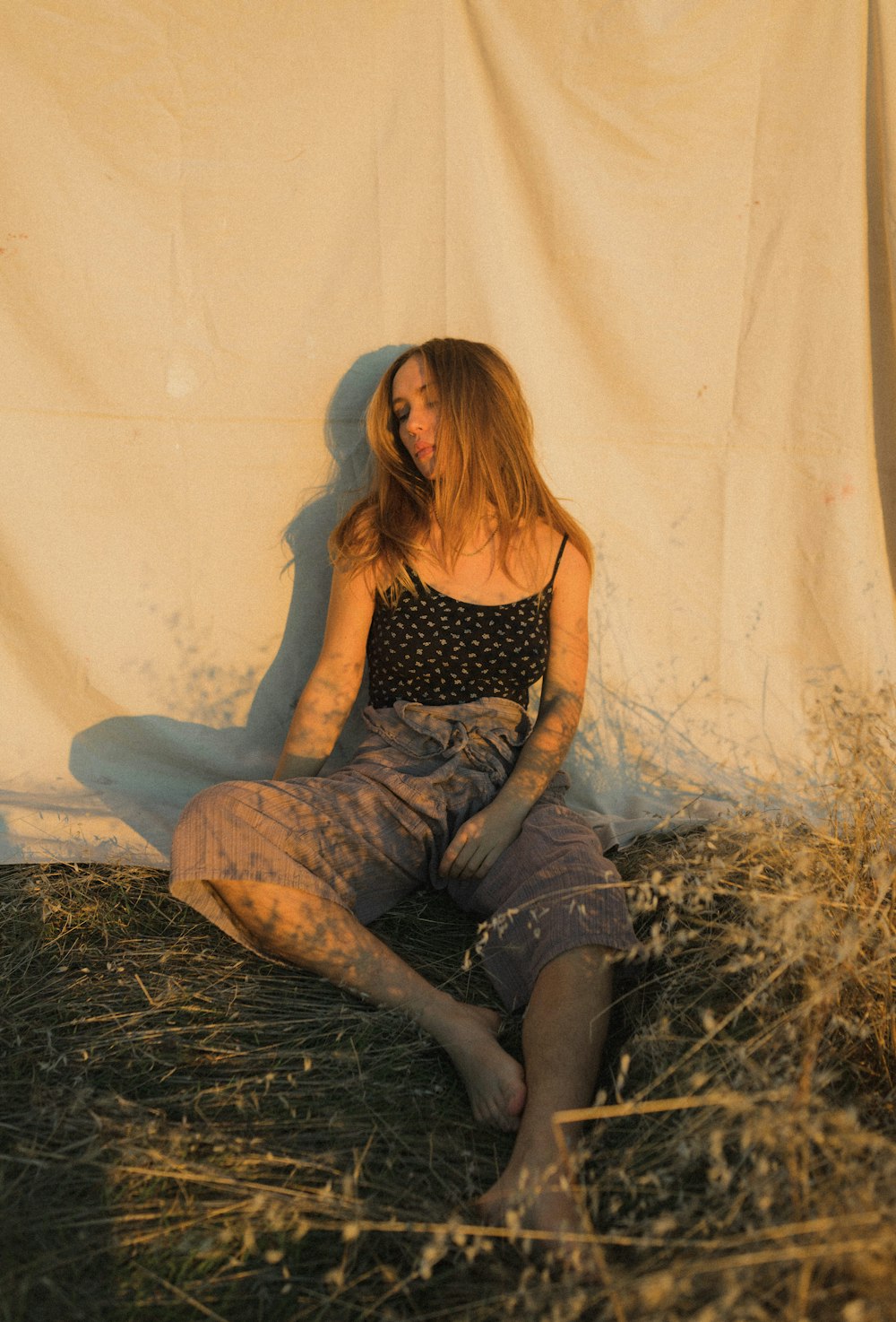 woman in black and white polka dot tank top and gray denim jeans sitting on brown