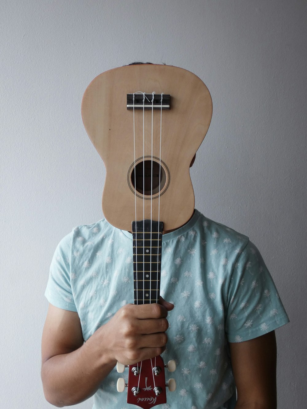 a man holding a ukulele in front of his face