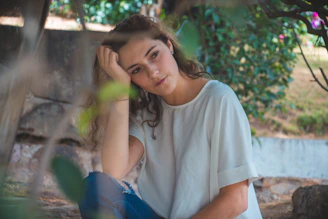 woman in white crew neck t-shirt and blue pants sitting on ground during daytime