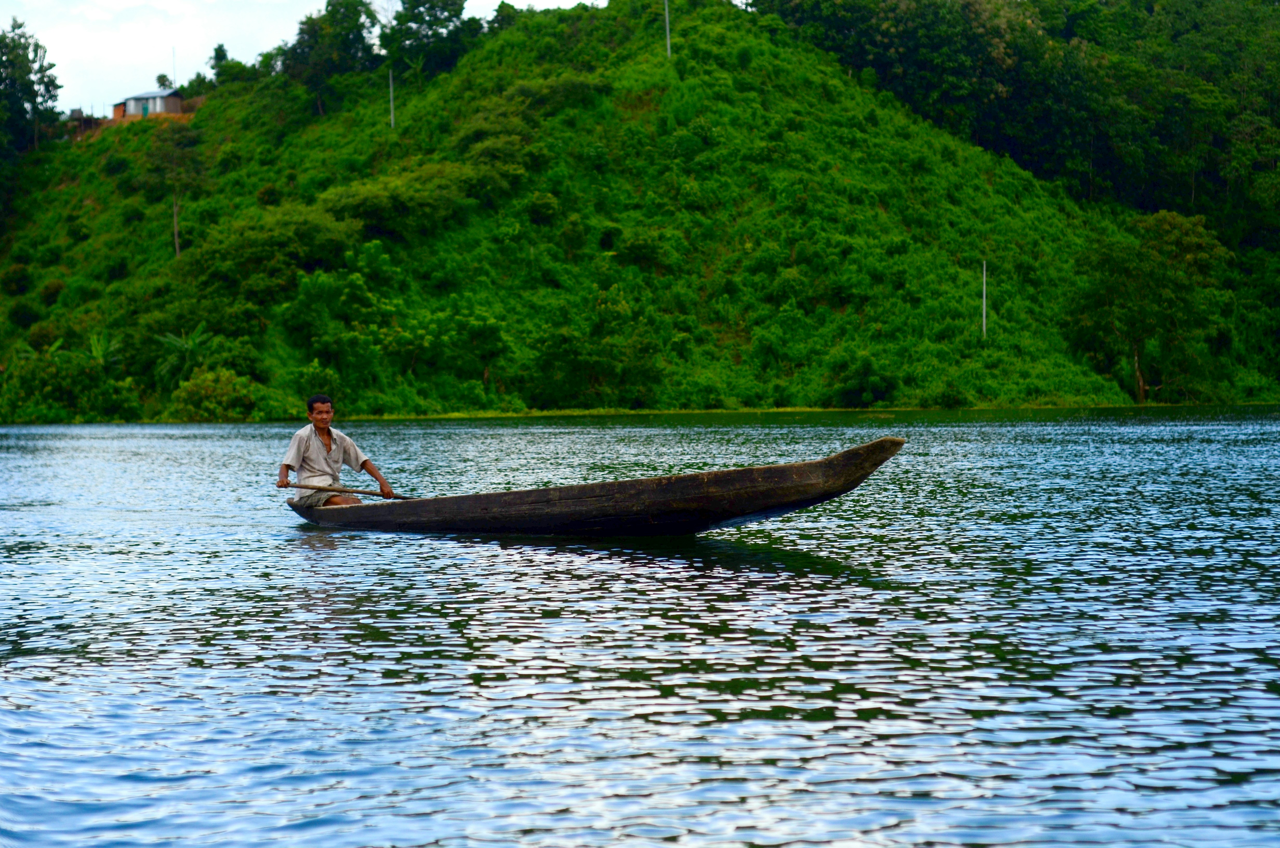 man in white shirt riding on canoe on lake during daytime