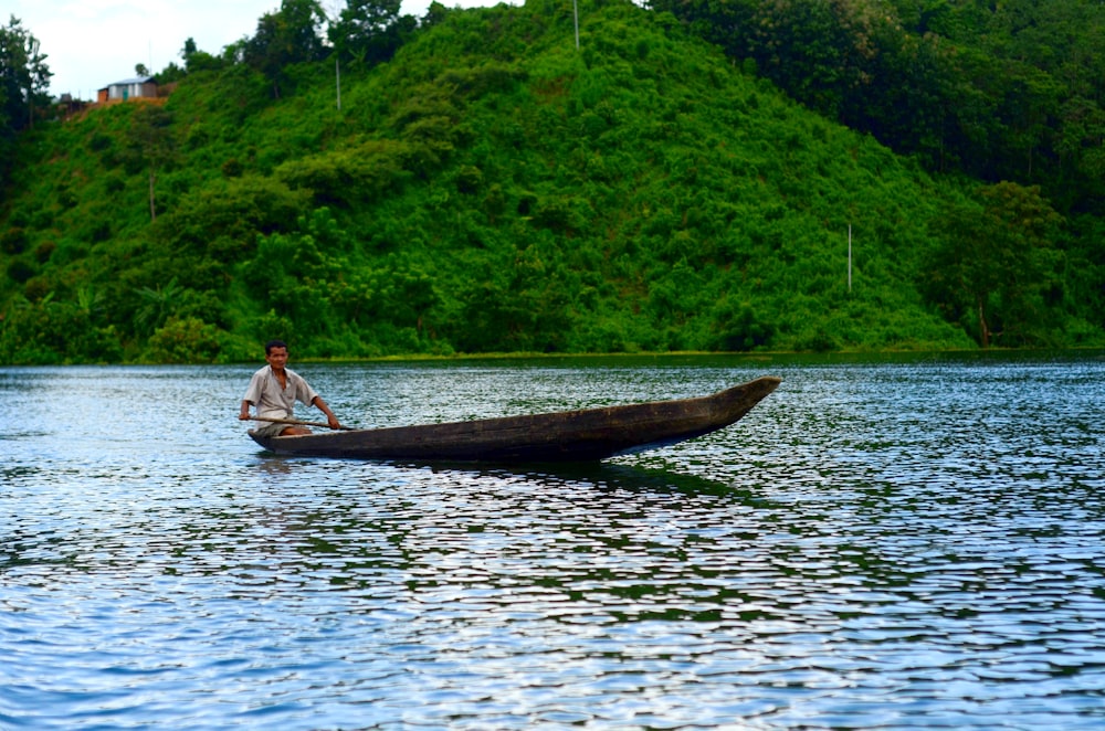 man in white shirt riding on canoe on lake during daytime