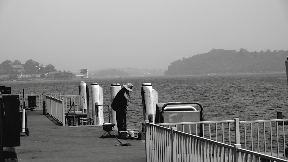 grayscale photo of woman walking on dock