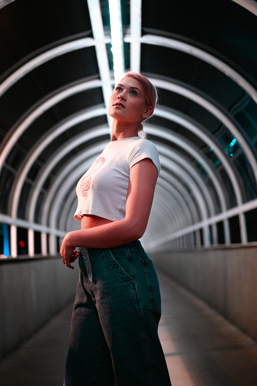 woman in white crew neck t-shirt and blue denim jeans standing on gray concrete floor