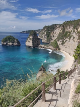 brown wooden fence on brown rocky mountain near blue sea under blue sky during daytime