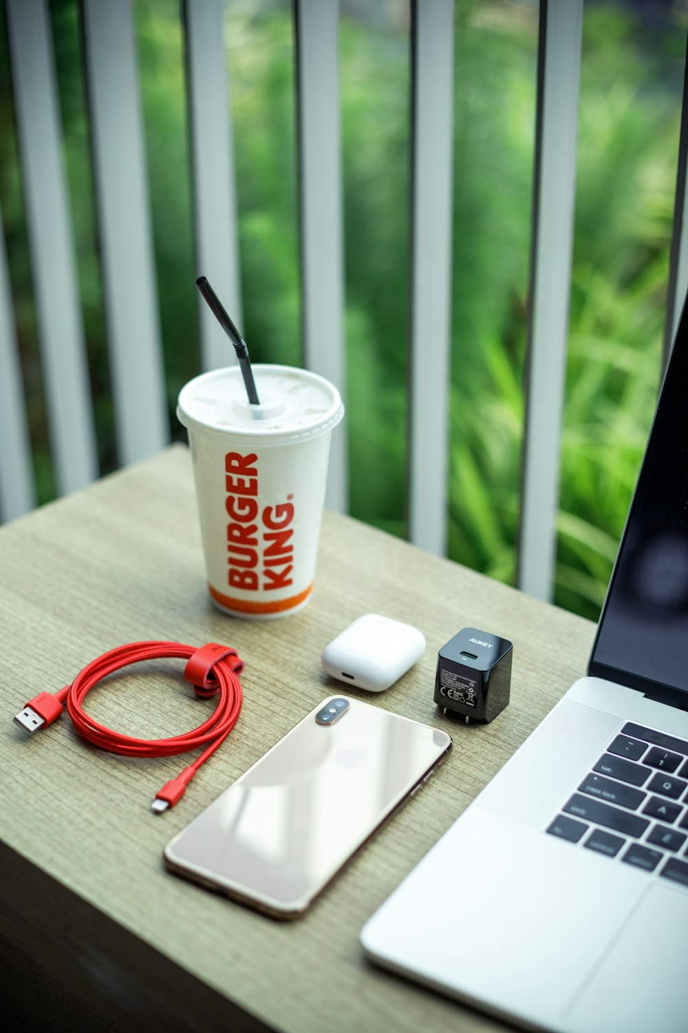 white and red disposable cup beside black and silver laptop computer on brown wooden table