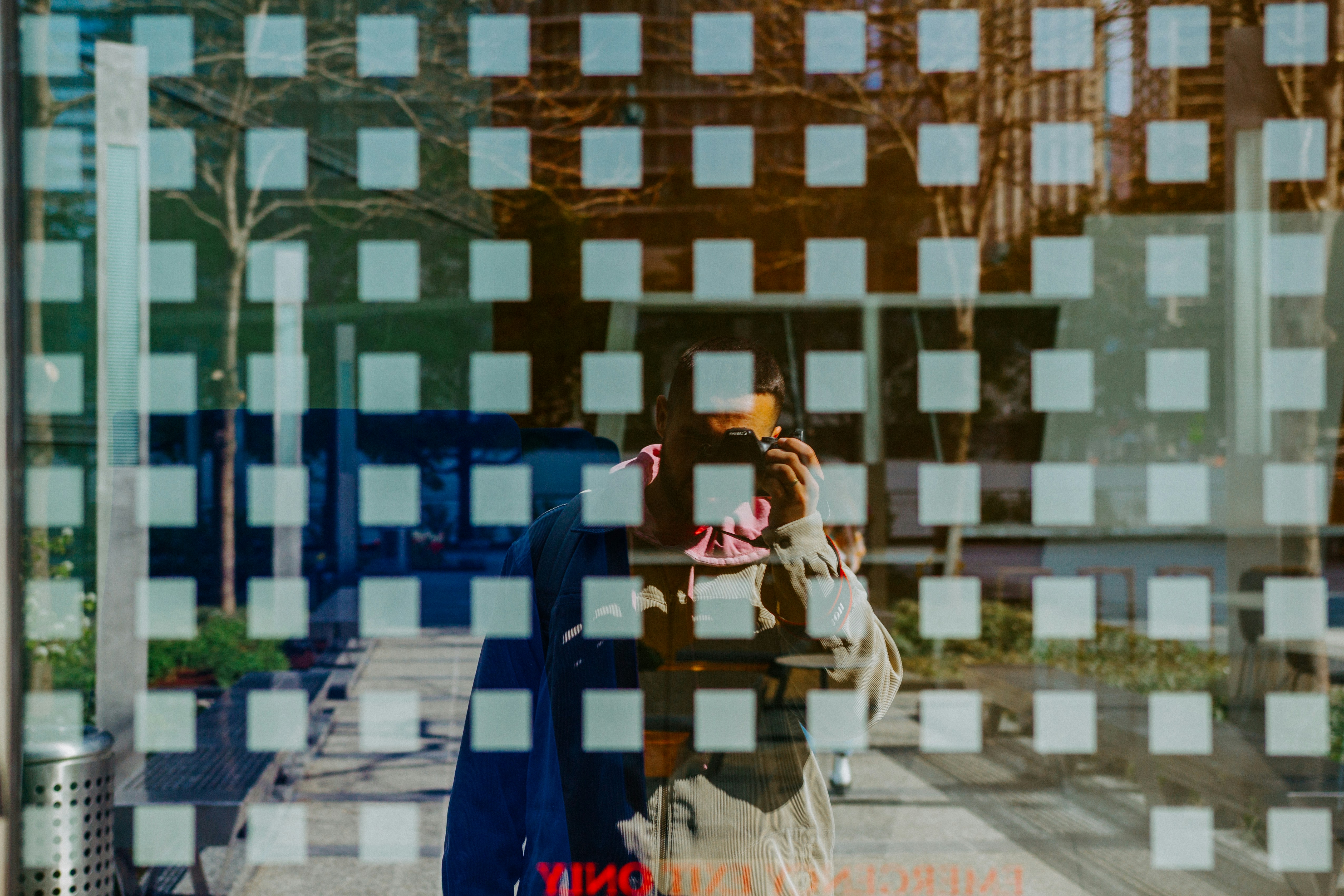 man in blue and brown long sleeve shirt standing on sidewalk during daytime