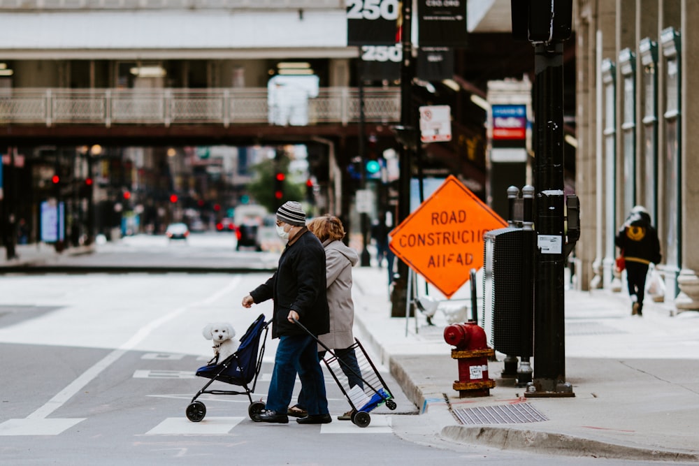 woman in black jacket and blue denim jeans riding on black and red stroller on street