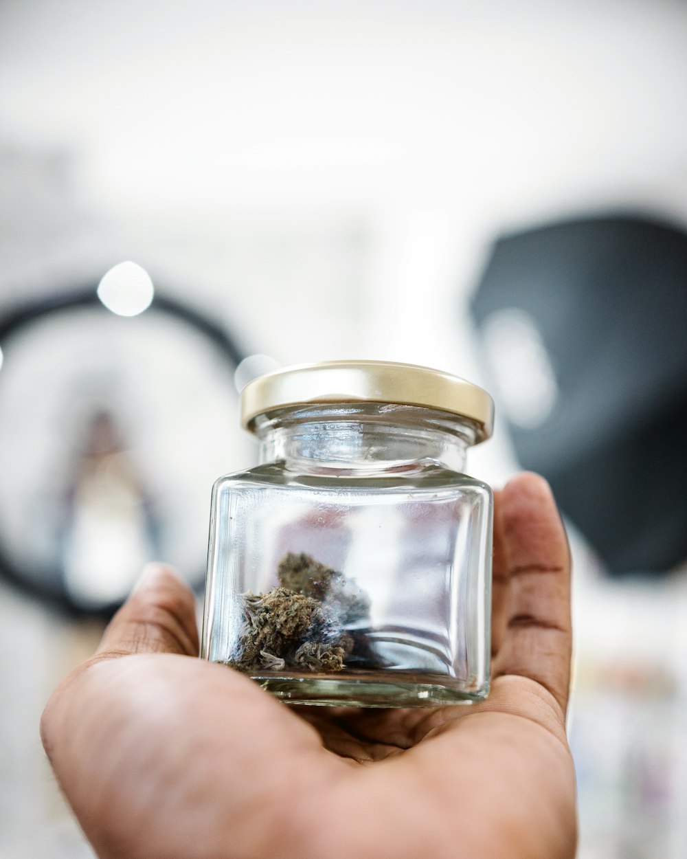 person holding clear glass bottle with brown powder