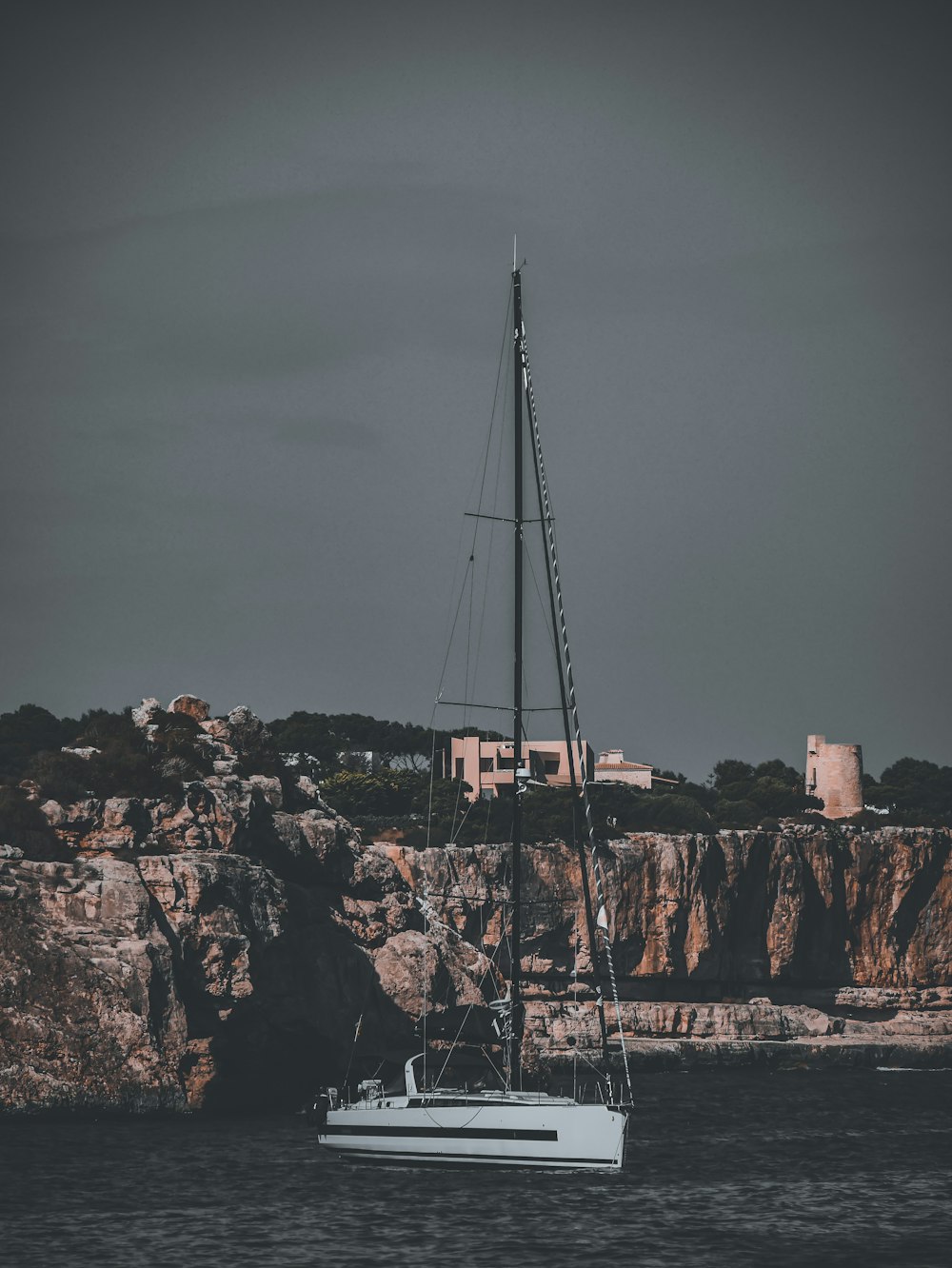 white sailboat on brown rock formation during daytime