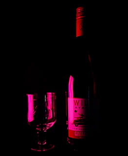 A sensual scene with a wine-colored toy resting beside soft silk fabric.