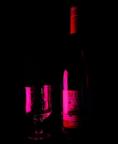 A sensual scene with a wine-colored toy resting beside soft silk fabric.