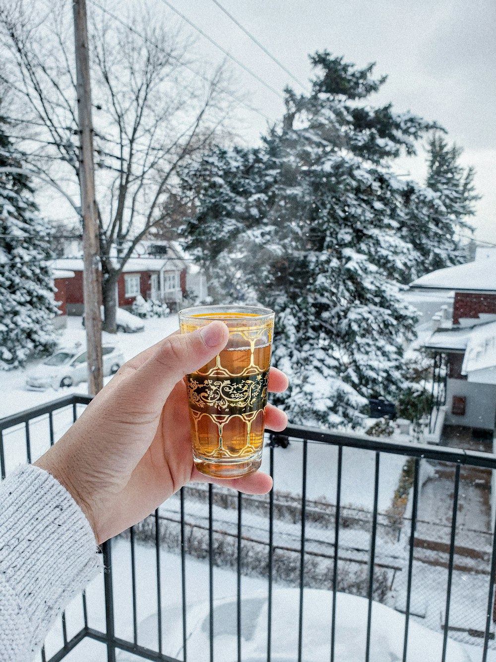 person holding clear drinking glass with brown liquid