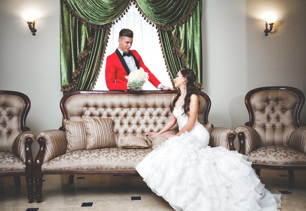 woman in white wedding gown sitting on brown and beige sofa