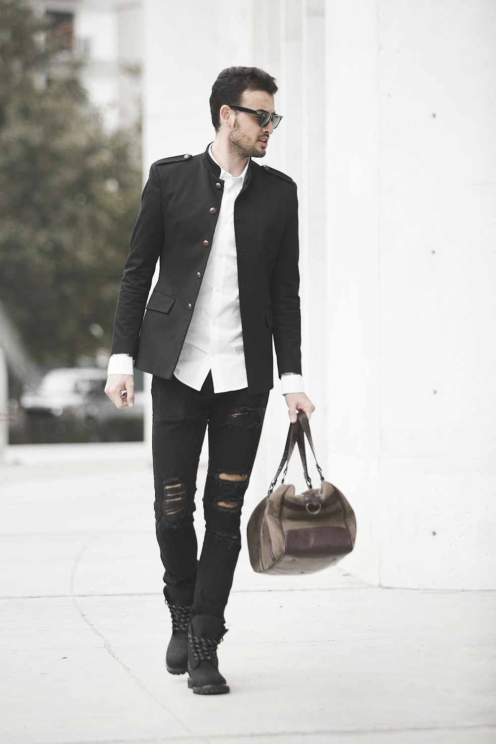 man in black suit holding brown leather handbag