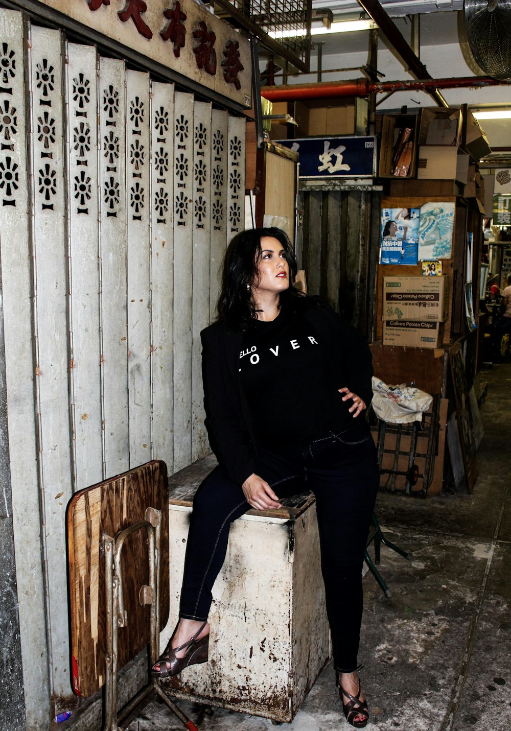 donna in camicia nera a maniche lunghe in piedi accanto alla staccionata di legno bianca
