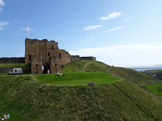 brown concrete building on green grass field under blue sky during daytime in Tynemouth