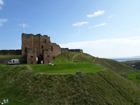 brown concrete building on green grass field under blue sky during daytime in Tynemouth