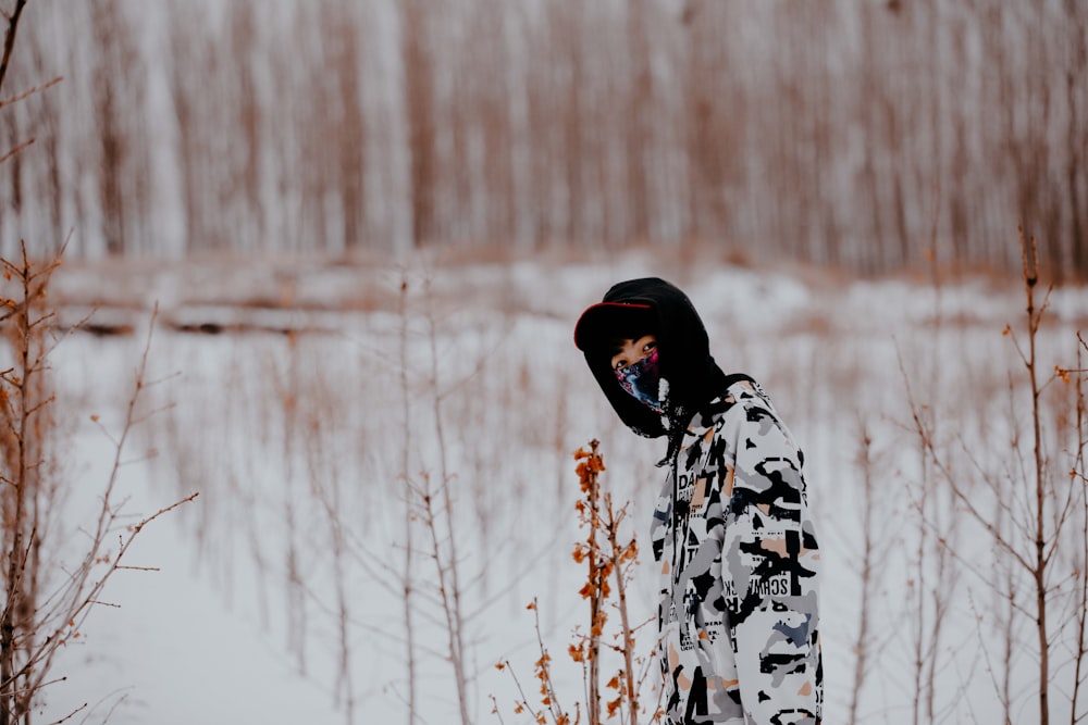 person in black and white floral hoodie standing on snow covered ground during daytime