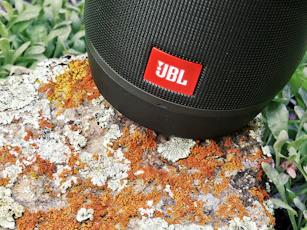 black jbl portable speaker on brown and white textile