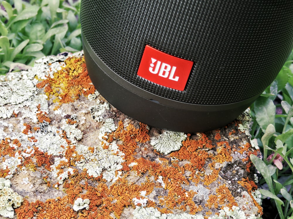 black jbl portable speaker on brown and white textile