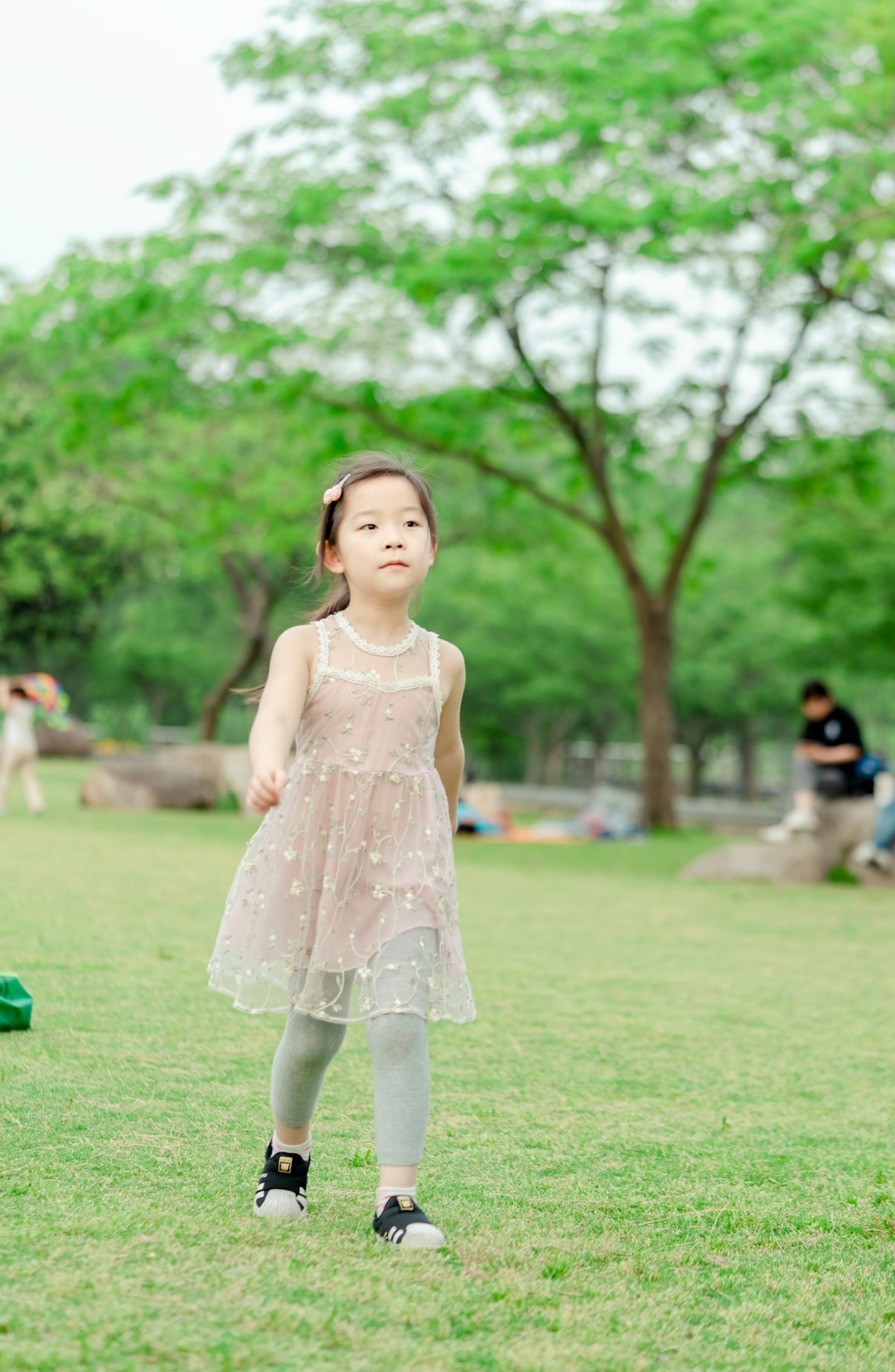 girl in pink floral dress standing on green grass field during daytime