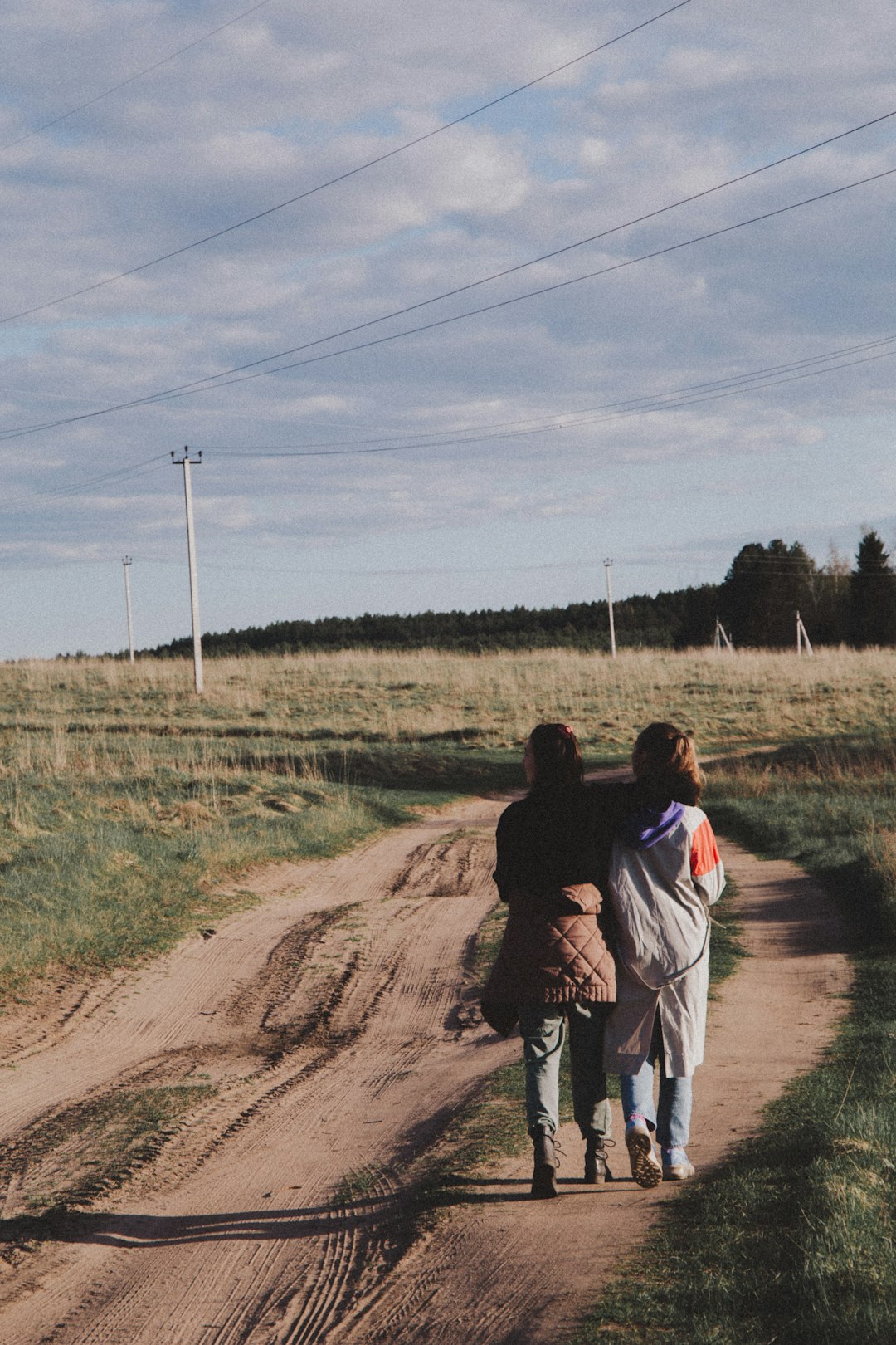 woman in black jacket and white pants standing on brown dirt road during daytime