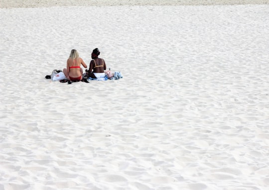 2 women sitting on beach sand during daytime in Maroubra Beach Australia