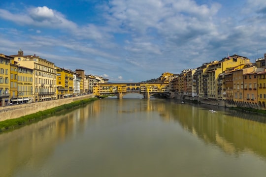 brown concrete building beside river under blue sky during daytime in Ponte Vecchio Italy