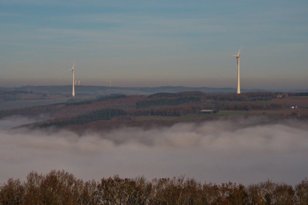 white wind turbine on green grass field near lake during daytime