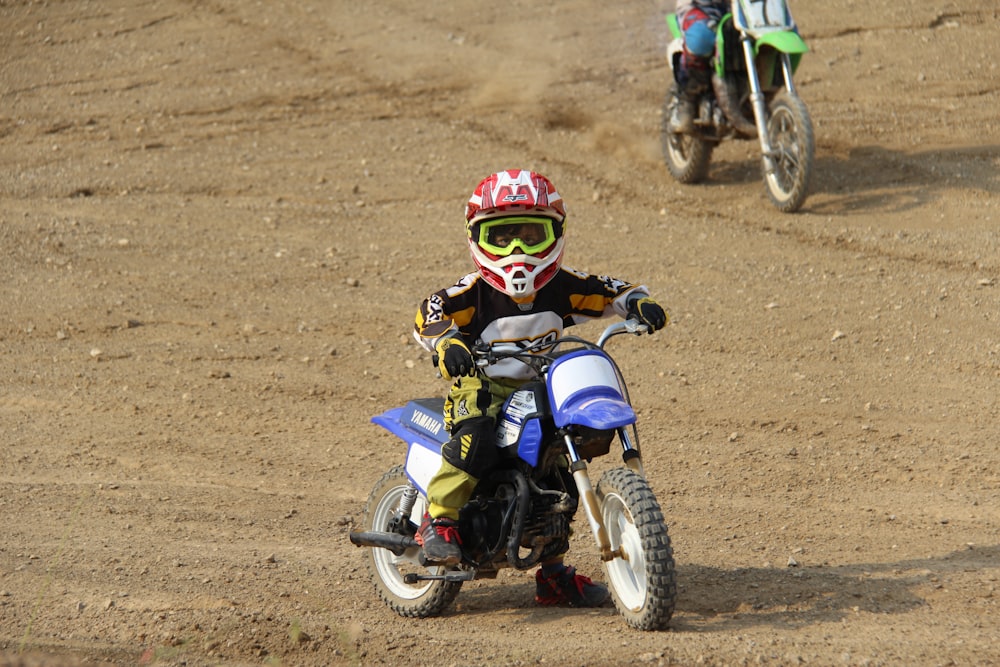 man in blue and red motorcycle suit riding blue and white motocross dirt bike