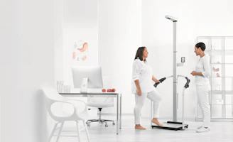 woman in white blazer and white pants standing beside white table