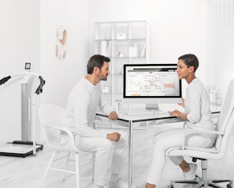 man in white dress shirt sitting on white chair in front of computer